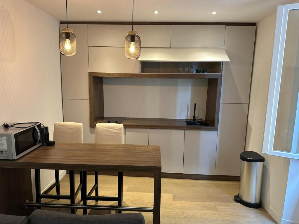 cocina con mesa de madera con sillas y microondas en Studio charmant et confortable, en Beausoleil