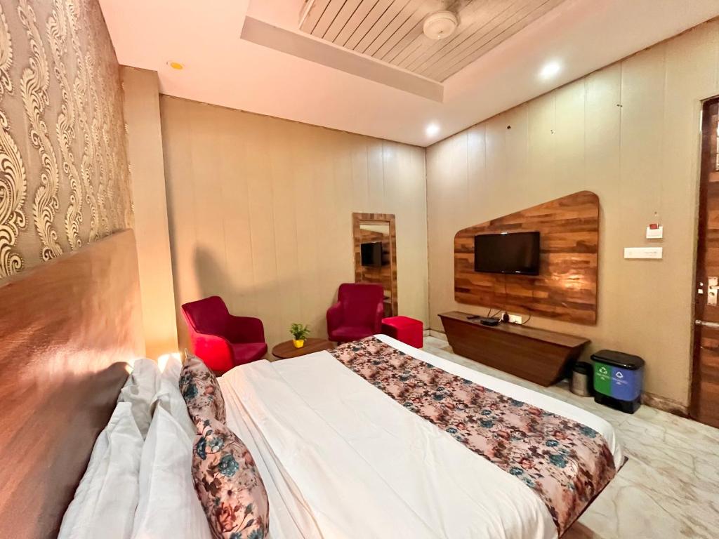 a hotel room with a bed and two red chairs at Hotel The Pearl, Zirakpur - A Luxury Family Hotel in Chandīgarh