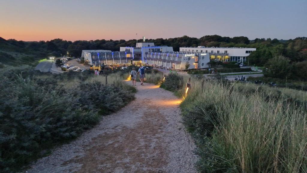 een paar mensen die over een onverharde weg lopen bij Strandhotel Westduin in Koudekerke