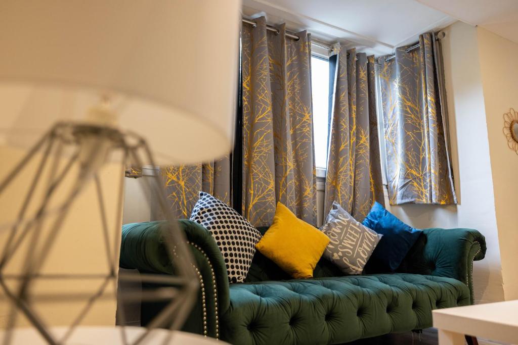 Remarkable 3-Bed Apartment in London في لندن: أريكة خضراء مع وسائد تقف أمام النافذة