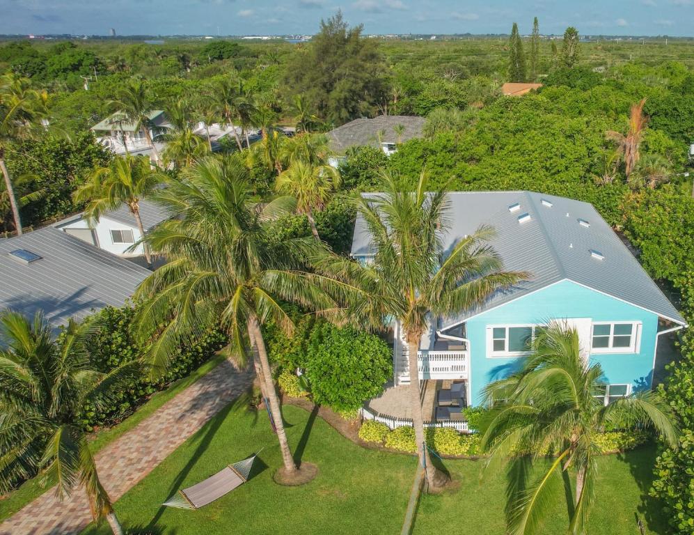 an aerial view of a blue house with palm trees at Hutchinson Island Beachfront - 2bd, 2ba Ensuite in Fort Pierce