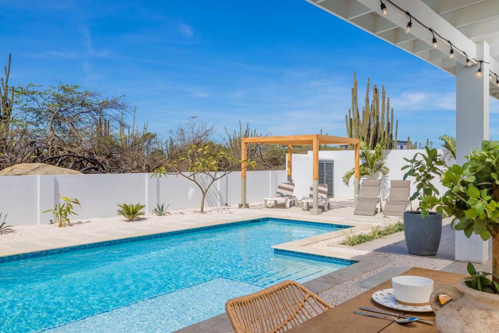 una piscina en un patio trasero con mesa y sillas en Luxury Villa Marcos - Private - Large pool, en Noord