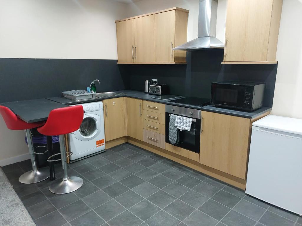a kitchen with a washing machine and a red chair at 2 large bedroom apartment- WIFI & Parking in Fleetwood