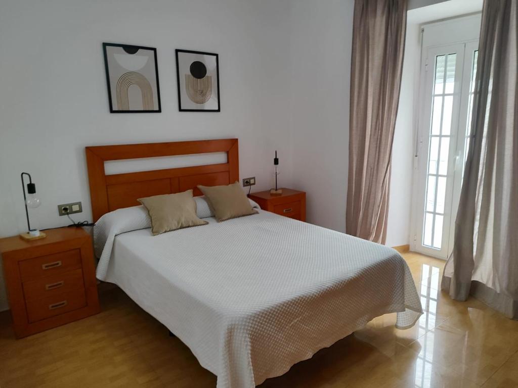 a bedroom with a large bed and two windows at San Francisco in Tarifa