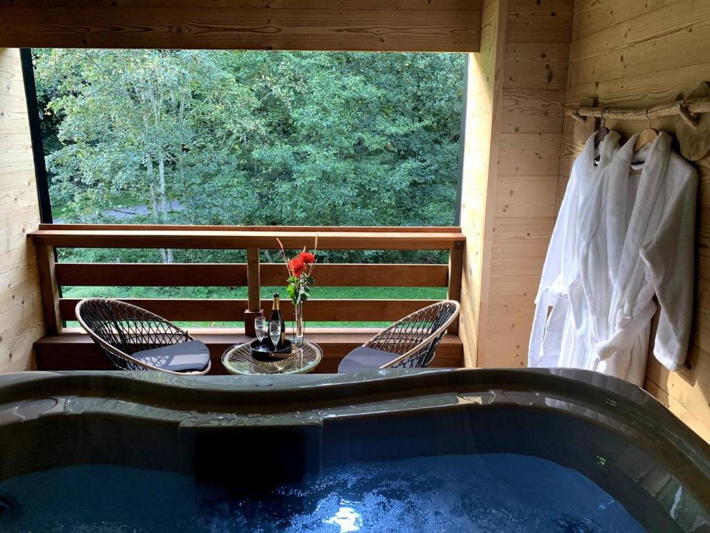 a hot tub in a cabin with a table and chairs at L'Echappée Magique in Mandray