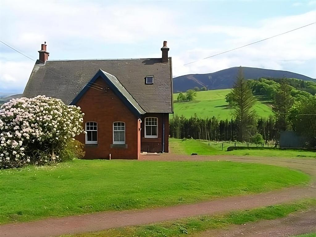 a small house with a green field and mountains in the background at The Gardener's House in Covington