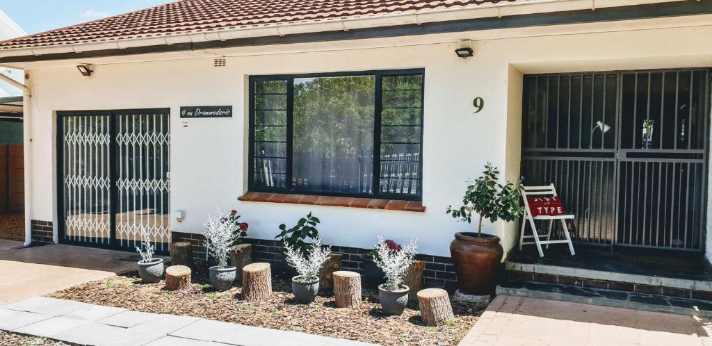 a house with black gates and potted plants in front of it at 9 on Drommedaris in Stellenbosch