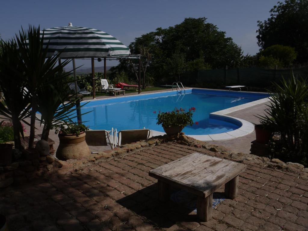 a swimming pool with a wooden bench and a table at Casa Vacanze Laura in Caltanissetta