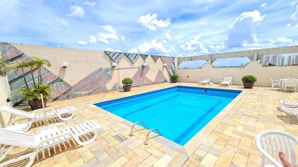 uma piscina com cadeiras brancas e uma piscina em TrevizZo no Hotel Astran em São Bernardo do Campo