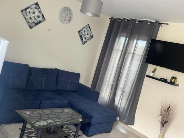 - un salon avec un canapé bleu et une table dans l'établissement Maison Goussainville - Aéroport ROISSY CHARLES DE GAULLES & PARIS, à Goussainville