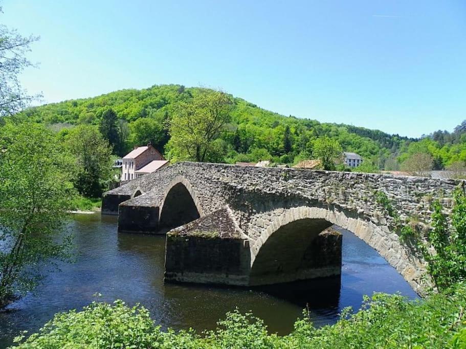 een oude stenen brug over een rivier met bomen bij Le Kinfolk studio in Châtel-Guyon