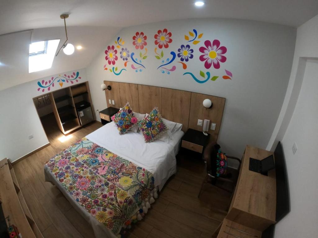 una camera da letto con un letto con fiori sul muro di Platero Hotel ad Ayacucho