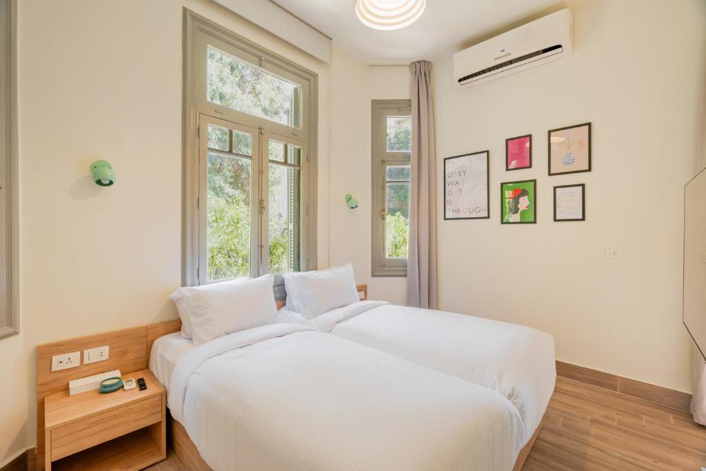 Un dormitorio con una gran cama blanca y una ventana en Brassbell studios in Zamalek en El Cairo