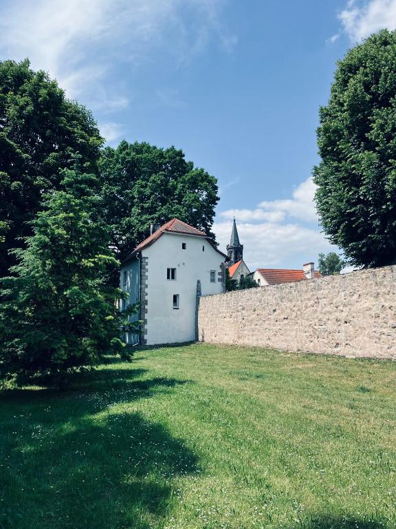 a white building in a field next to a wall at Dom w murach in Lwówek Śląski