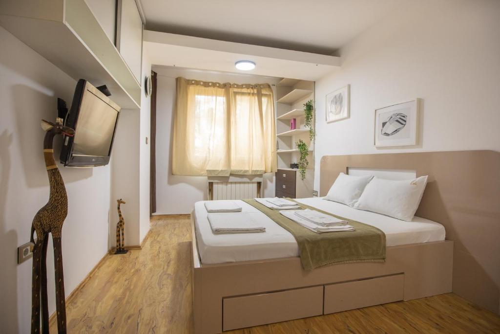 a small bedroom with a bed and a tv at Apartment DE LUXE FAMILY in Niš