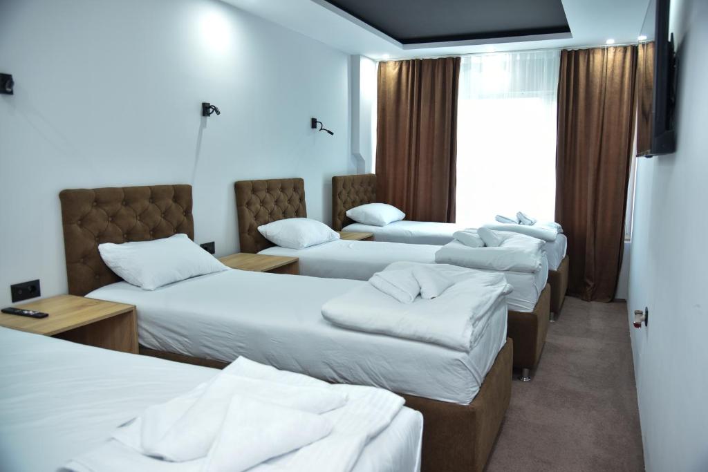 a group of four beds in a room at Apartmani COLOSSEUM in Bratunac