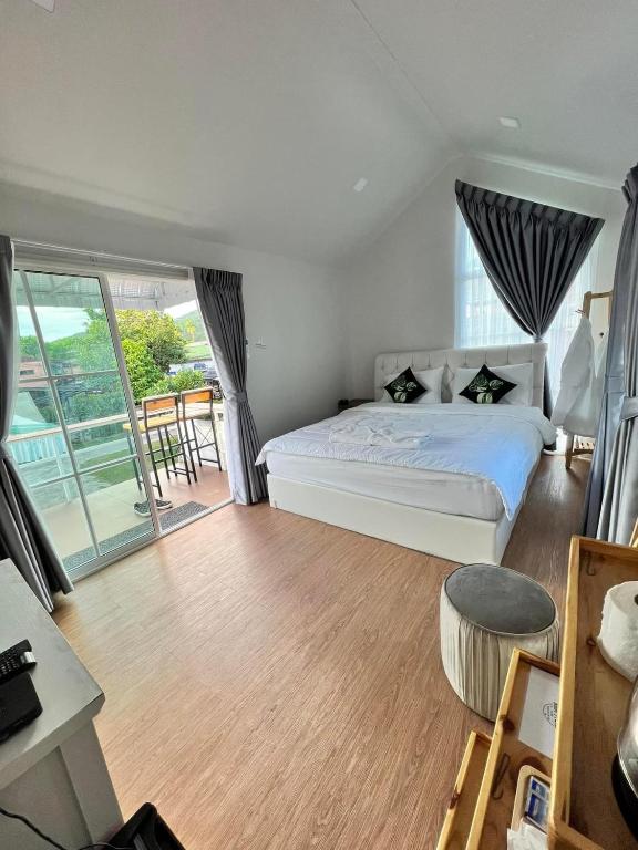 a bedroom with a white bed and a balcony at Baan Pranai In Pai in Pai