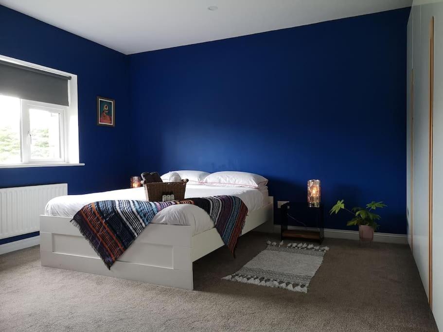 a blue bedroom with a white bed and a blue wall at Tranquil Country Escape West Coast Adventure Awaits in Galway