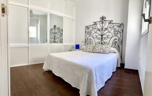 a white bedroom with a bed with a head board at Alcalá zona Centro in Alcalá la Real