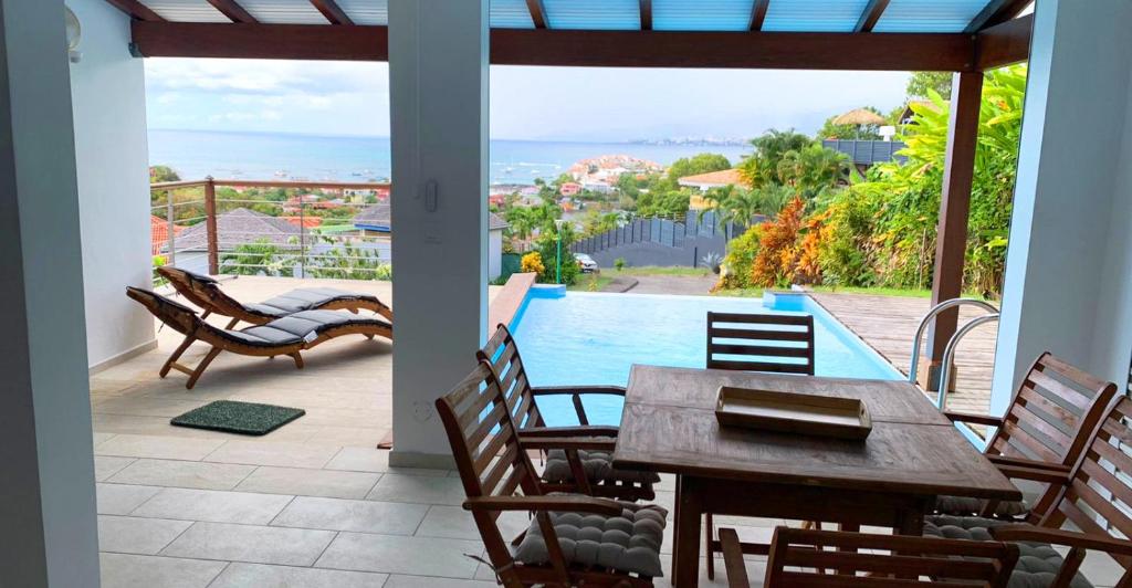 une terrasse avec une table, des chaises et une piscine dans l'établissement Appartement T3 -Villa Les Bougainvilliers, à Les Trois-Îlets