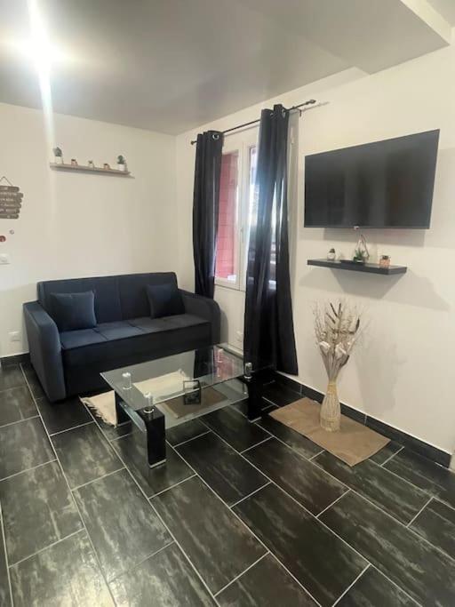 un salon avec un canapé bleu et une table en verre dans l'établissement L8 - Villiers-le-Bel proche ROISSY & PARIS, à Villiers-le-Bel