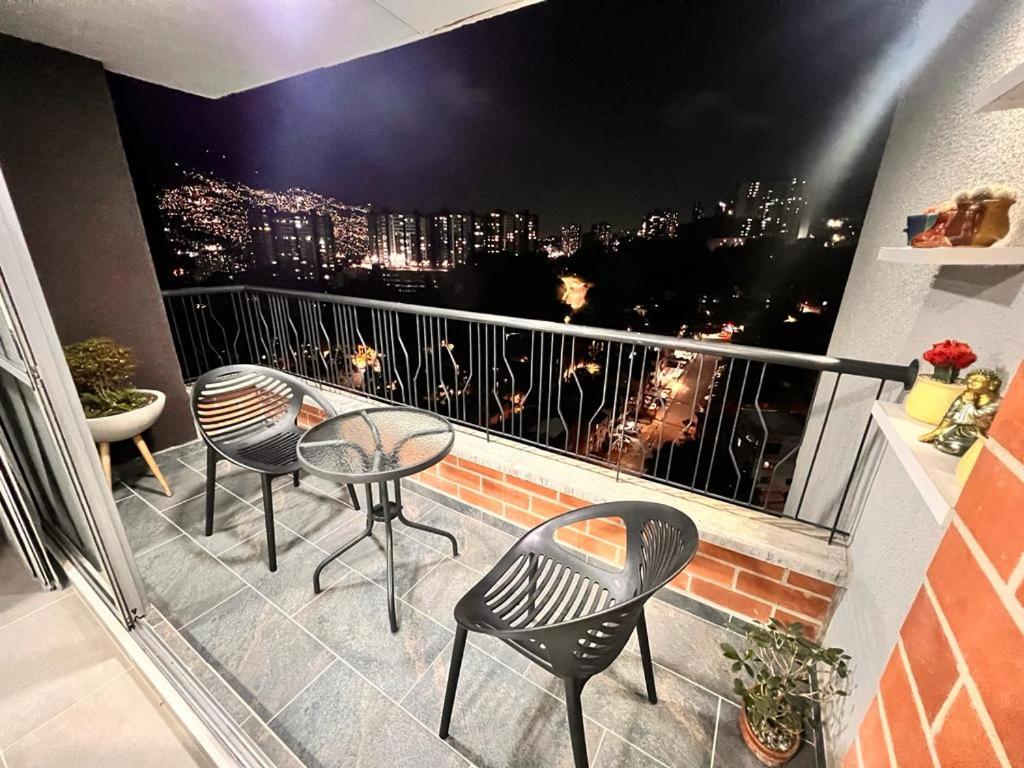 a balcony with chairs and tables and a view of a city at AlOJAMIENTO EN BELLO in Bello
