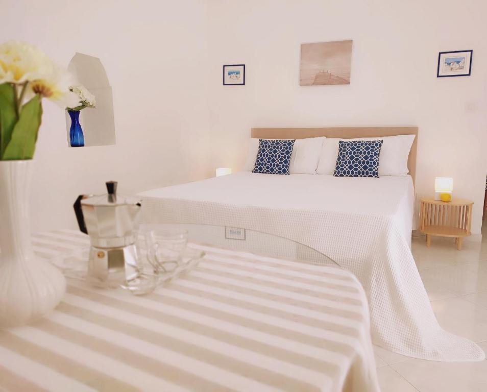 a white bedroom with a bed and a vase of flowers at L'Archetto romantic suite in the center of Anacapri in Anacapri