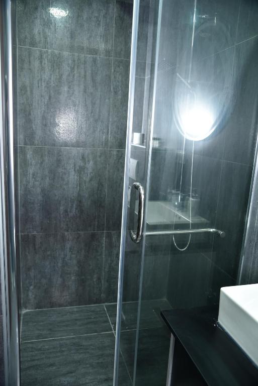 a shower with a glass door and a light in a bathroom at Apartmani COLOSSEUM in Bratunac