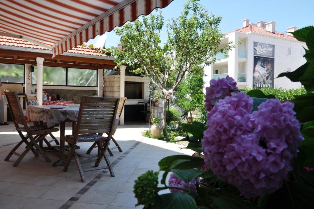 a patio with a table and chairs and purple flowers at Uvala Apartment in Dubrovnik