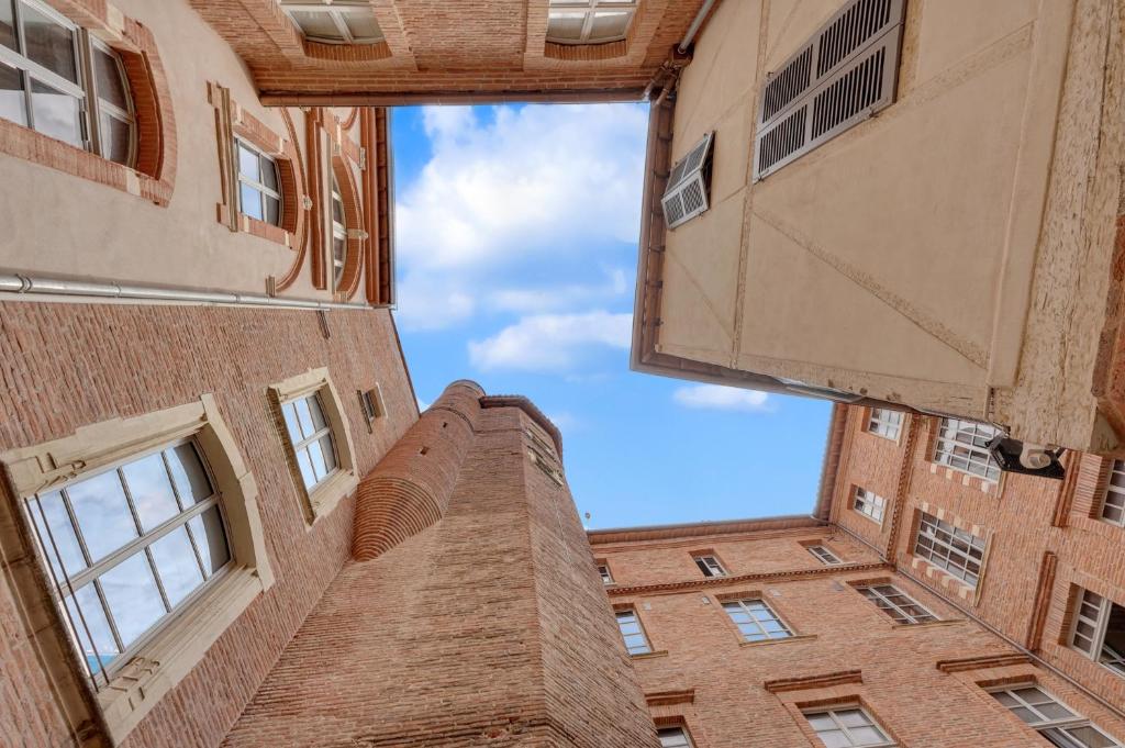a view of a tall brick building looking up at the sky at Les Relais du Capitole - Appartements d'hôtes in Toulouse