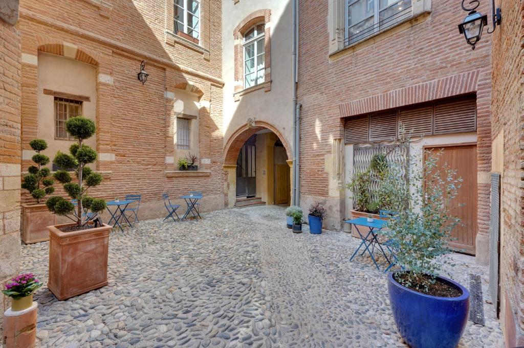 a courtyard with potted plants and tables and buildings at Les Relais du Capitole - Appartements d'hôtes in Toulouse