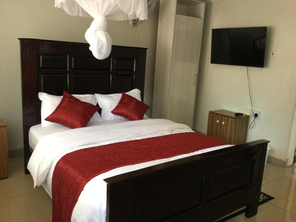 una camera da letto con un grande letto con cuscini rossi di Milimani Comfort a Kisumu