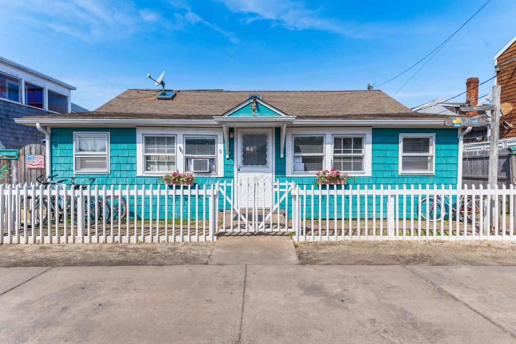 una casa azul con una valla blanca delante de ella en The Blue Parrot Cottage, en Ocean Beach