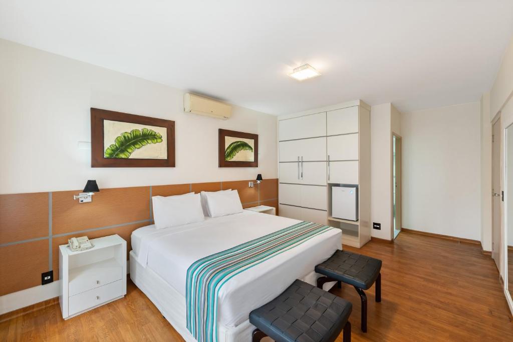 a bedroom with a large white bed and two chairs at Capcana Hotel Jardins in Sao Paulo