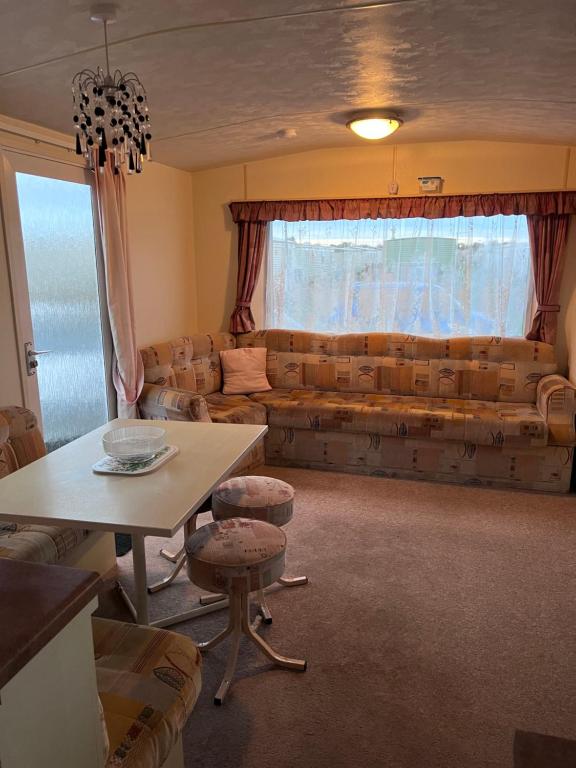 una sala de estar con un sofá y una mesa en S422 Golden Palm 8 Berth Caravan, en Chapel St. Leonards