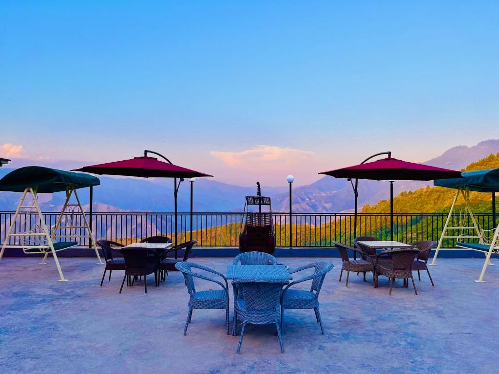 un patio con mesas, sillas y sombrillas en Pinerock Resort, Mussoorie ! Luxury Rooms ! Mountain View ! Open Terrace ! Cafe, en Mussoorie