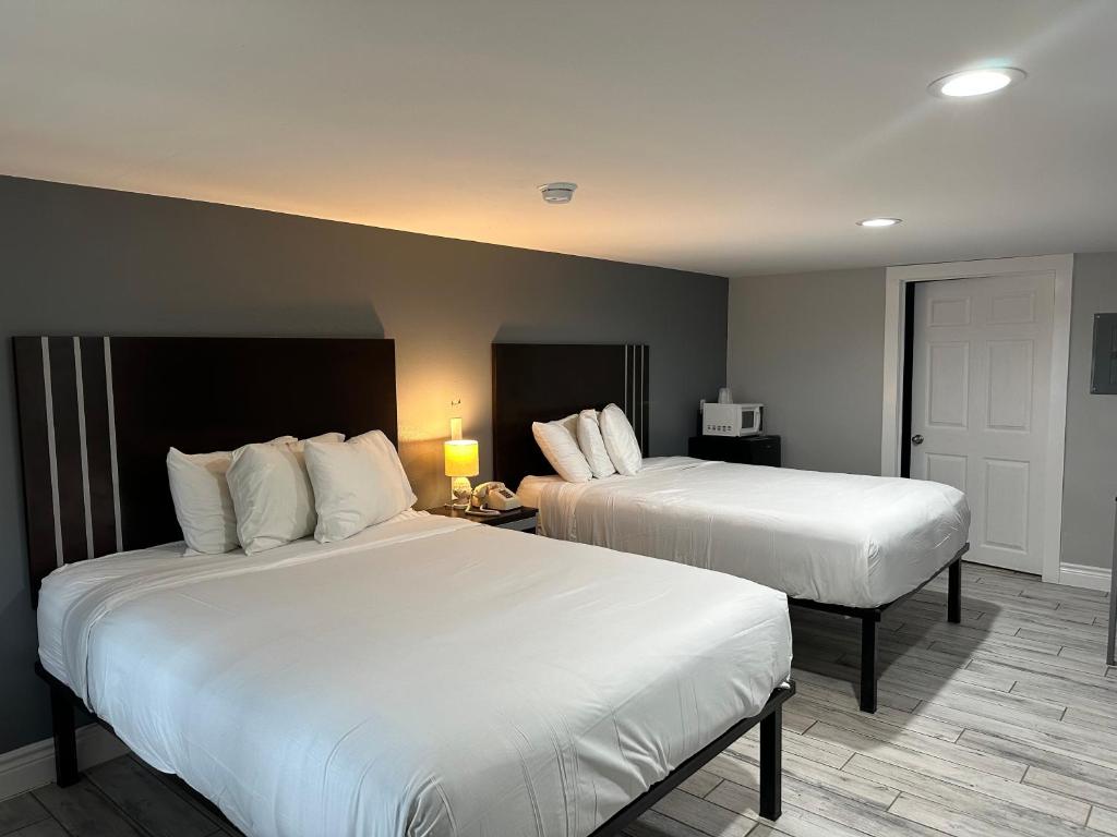 2 camas en una habitación de hotel con sábanas blancas en Village Inn Motel en Rockport