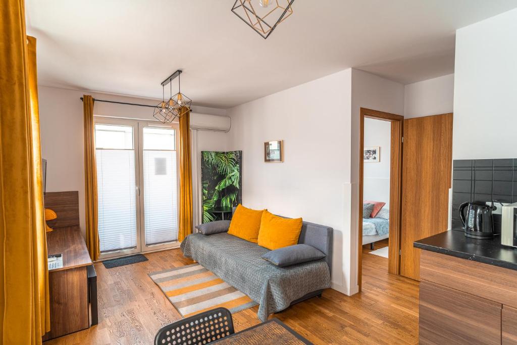 salon z kanapą z pomarańczowymi poduszkami w obiekcie Apartament Chmielna Loft w Krakowie