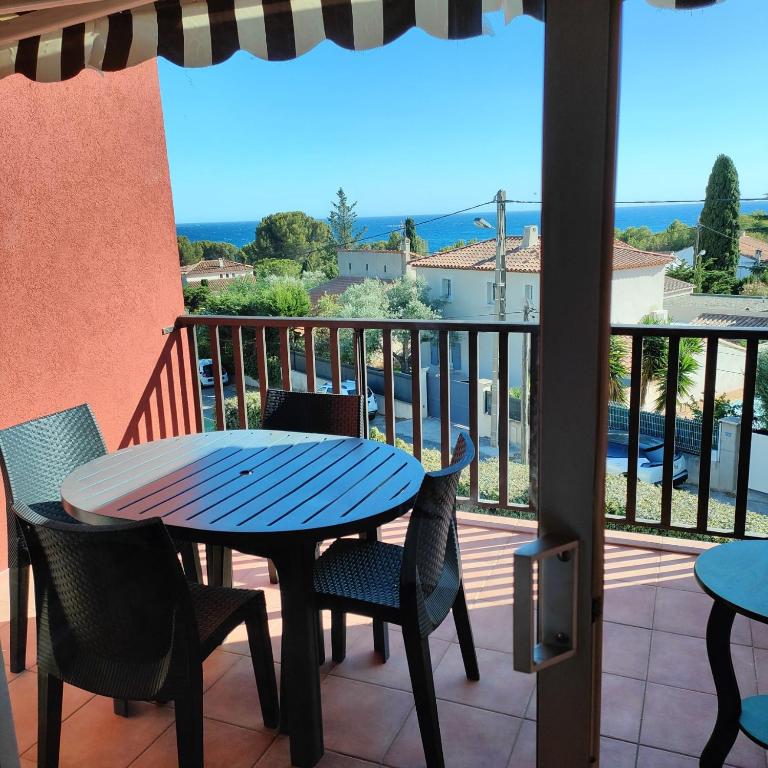 patio con mesa azul y sillas en el balcón en Studio vue mer, en Bandol