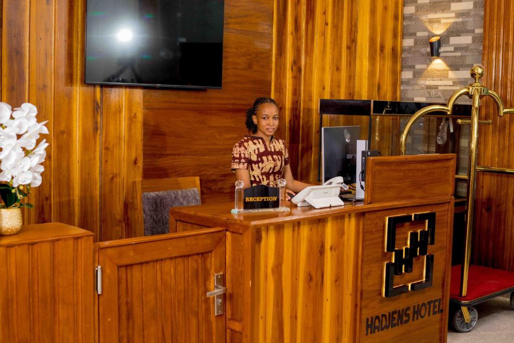 una mujer parada en un mostrador en una oficina en HADJENS HOTEL en Mwanza