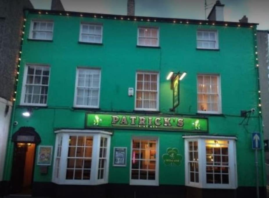 a green building with a sign on the front of it at Patrick's Bar in Bangor