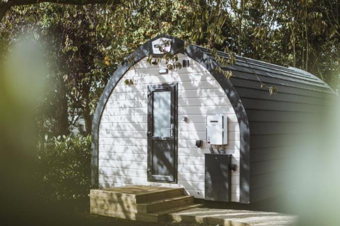 a small white building with a door and stairs at Carlton Manor Pods in Aldbrough