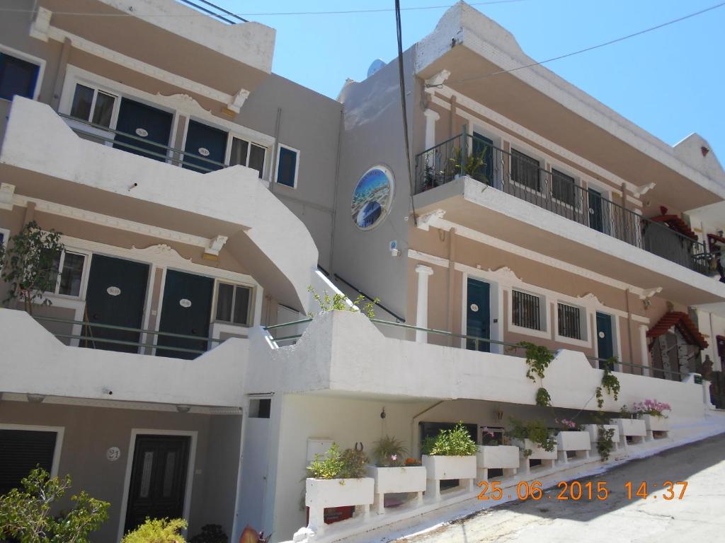 un grand bâtiment blanc avec des balcons blancs et des plantes dans l'établissement Mina Apartments, à Poros