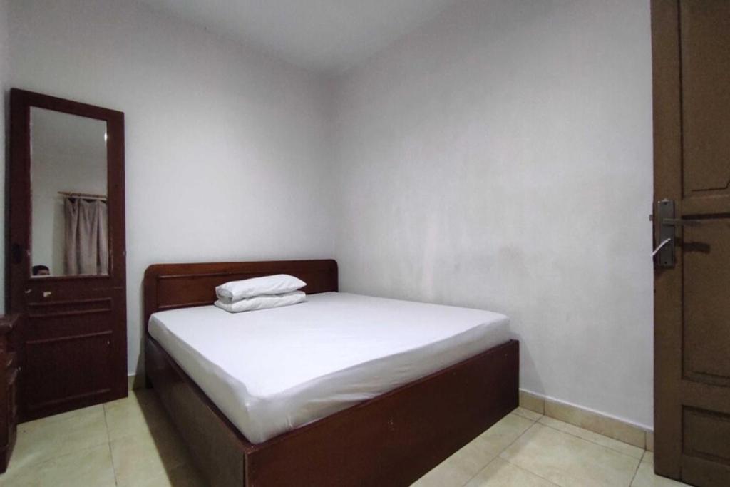 a small bedroom with a bed with white sheets at OYO 93175 Wisma Syariah Dian in Barru