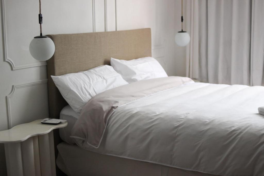 um quarto com uma cama com lençóis brancos e uma mesa em Alójate en el corazón de Mendoza . Angélica Downtown em Mendoza