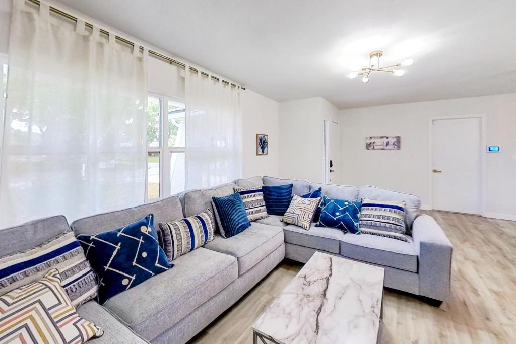 a living room with a gray couch with blue pillows at Tropical Vibe in Dunedin