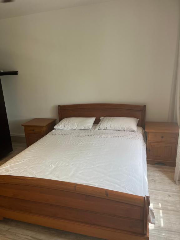 1 dormitorio con cama de madera con sábanas y almohadas blancas en Luxury villa en Tamarin