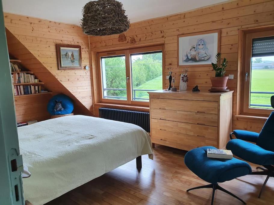 1 dormitorio con 1 cama, 1 silla y ventanas en Lumière et verdure, maison de campagne, en Miniac-Morvan