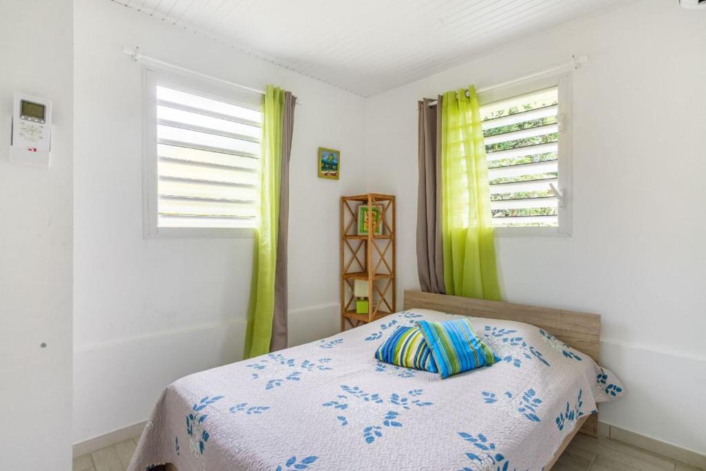 a bedroom with a bed and two windows at Ti-colibri ✓Iguana Village in Sainte-Luce