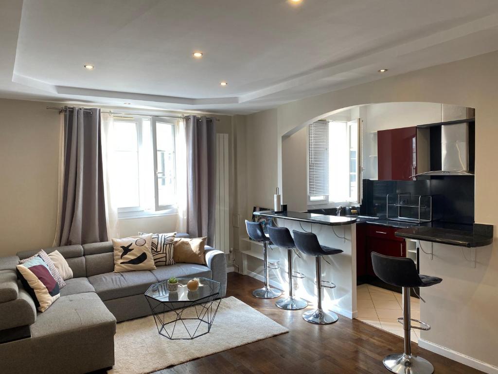 a living room with a couch and a kitchen at Bel appartement proche de Paris in Colombes